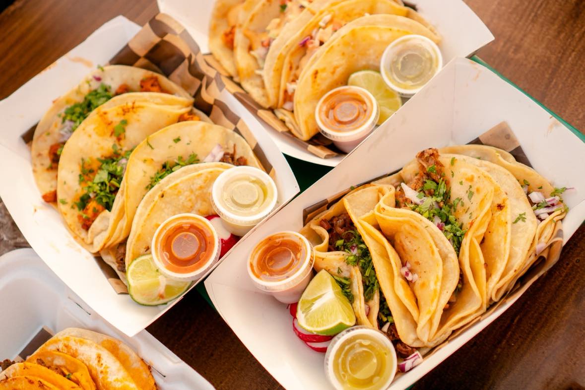 A group of tacos sitting on a wooden table.