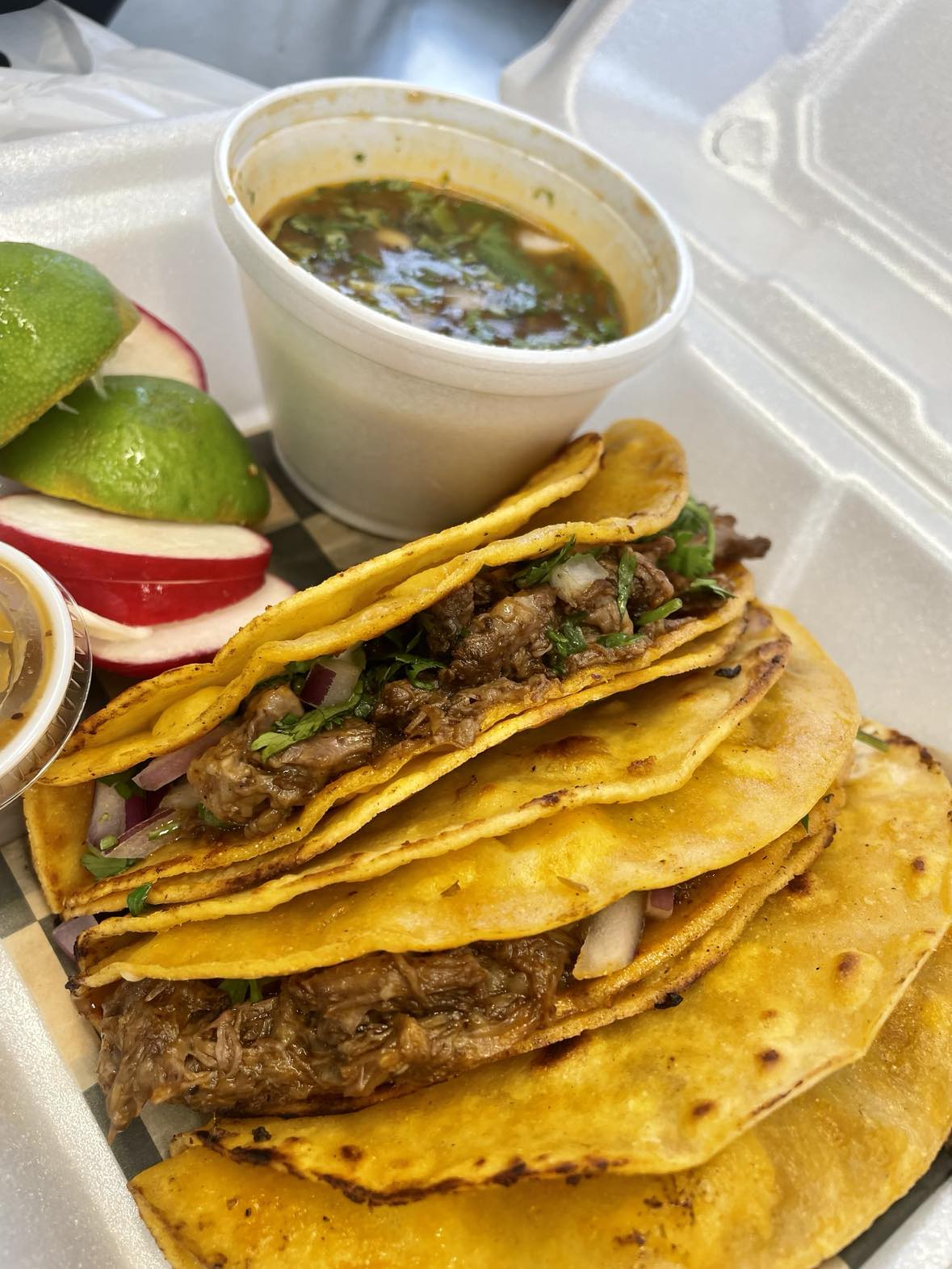 A tray of tacos with a side of guacamole.