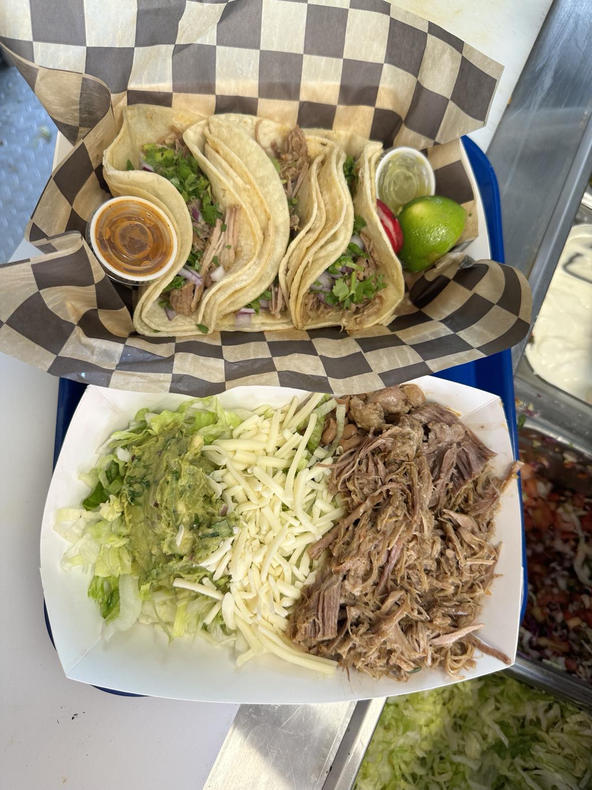 Two tacos on a tray with salsa and guacamole.